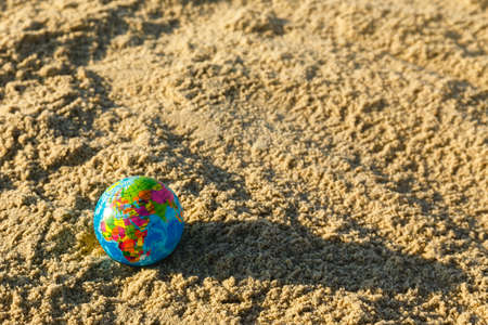 Globe of the planet  Earth on a sandy beach close up. Travel around the world concept.の写真素材