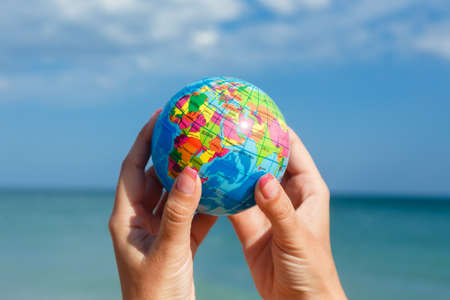 Woman holding globe of the Earth on a background of the sea. Concept ecology, peace,, save the planet Earth.の写真素材