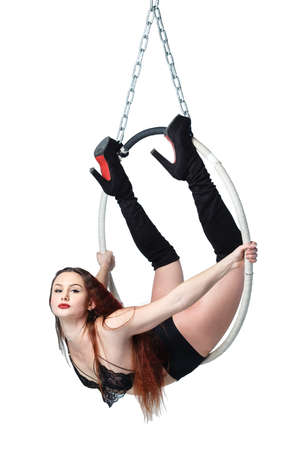 Aerial acrobat in a hoop. Young woman performs the acrobatic elements in the air ring. Studio shooting, isolated on white background.の写真素材