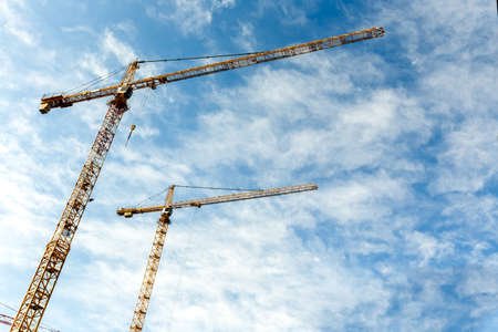 Two high tower cranes work on a construction of new homes