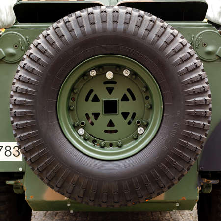 Spare wheel close-up mounted on the body of a combat car. Military industry concept.