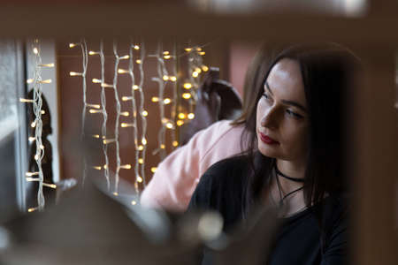 Portrait of a woman sitting near the window in a cafe. Looking to the window. Low key.