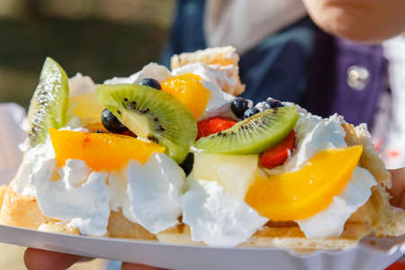 Fresh waffle cake with fruit and whipped cream on a holiday close-up.の写真素材