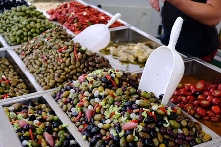 Various marinated olives for sale in a market window. Mediterranean delicacies, dietary healthy food.の写真素材