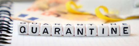 Word "Quarantine", Protective mask and Euro banknotes on a white paper note pad background. Financial crisis and coronavirus global pandemia. Shallow Depth of Field, Selective Focus.の写真素材