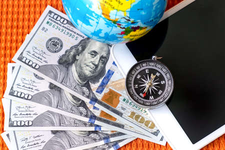Five Hundred American Dollars Bills, Compass, Globe of Planet Earth, tablet on a Fabric Background...