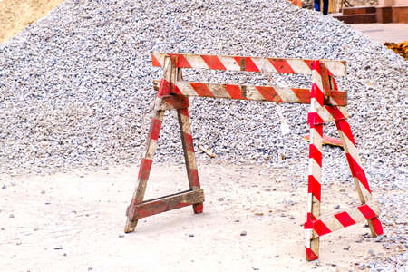 Wooden red white striped fencing roadblock and heap of rubble on a road construction at city street.の写真素材