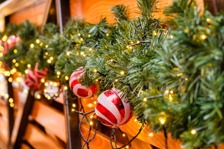 Wooden Retro Restaurant Building Decorated of Artificial Fir Tree with Lighting Garland and many Red and White Christmas Balls at Winter Day, no Snow.の写真素材