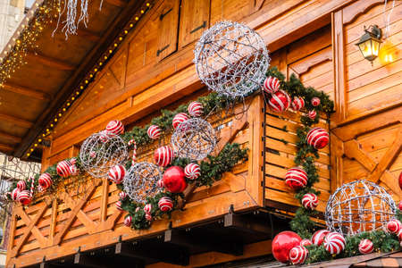 Balcony of Wooden Vintage Building Decorated of Artificial Fir Tree with Garland and many Red and White Christmas Balls at Winter Day, no Snow.の写真素材