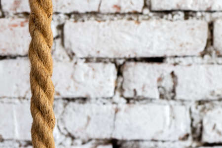 Rough braided rope against the background of a white brick wall in a luxury loft interior of a hotel...