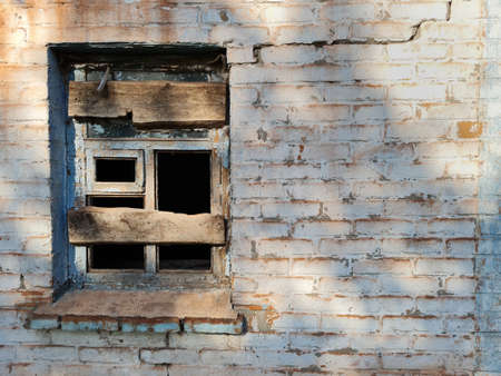 Texture of old aged white painted brick wall of abandoned house with window.の写真素材