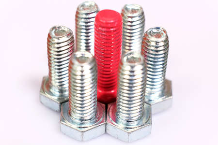 Close-up of pink bolt n a group of galvanized metallic screws. Not like everyone else, originality concept. Stainless steel bolts isolated on white background.の写真素材