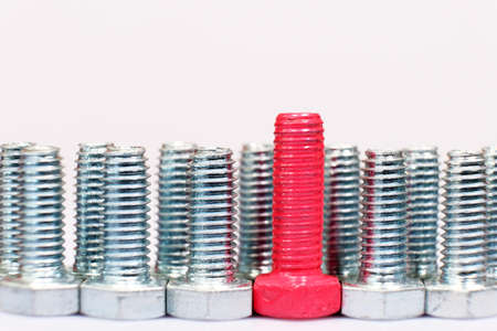 Close-up of red bolt in a group of galvanized metallic screws.の写真素材