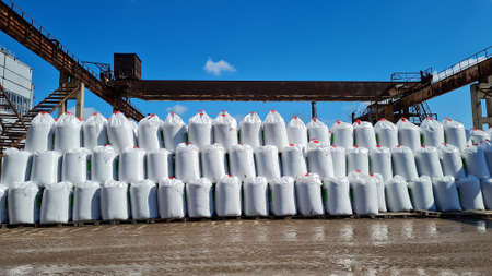 Many white big bags with chemical fertilizers in a warehouse outdoors. Stack of sacks in a 3 row on a blue sky background at sunny day.の写真素材