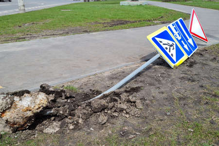 Damaged Broken Traffic Signs With Bus Direction Arrow and Pedestrian Crossing Road are Laying on the ground on Urban Street.の写真素材