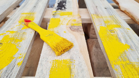 Paint brush painted with yellow color lie on a wooden pallet.の写真素材