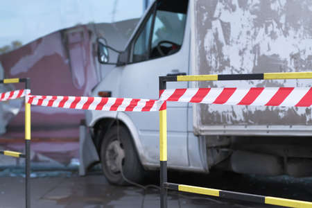 White lorry collided with a glass wall of shopping mall. Road accident site is isolated and fenced off with a signal tape.の写真素材