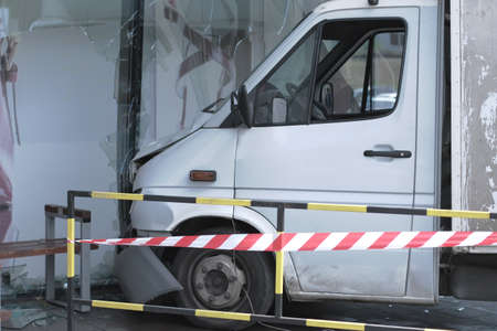 White lorry collided with a glass wall of shopping mall. Accident site is isolated and fenced off with a signal tape.の写真素材