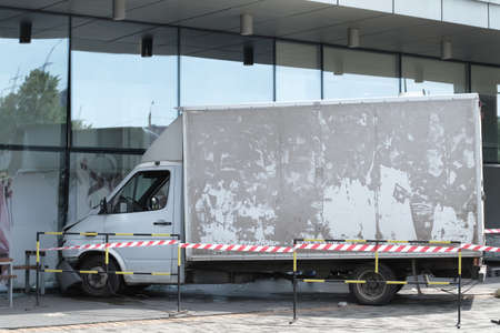 White lorry collided with a glass wall of shopping mall. Accident site is isolated and fenced off with a signal tape.の写真素材