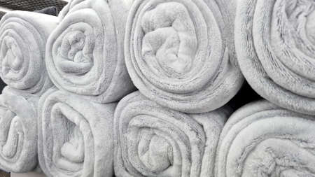 Rolled gray blankets  in a store for sale. Soft fluffy beige plaids sells in a shop shelf.