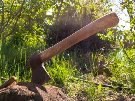 old vintage iron ax sticks out in a stump on a farm on a sunny summer day. Backlight.の写真素材