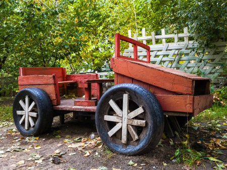 Wooden red handmade vintage car for children fun playing stand in a park at autumn day.