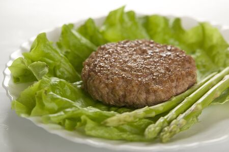 Meat rissole with lettuce and asparagus on the white plateの写真素材