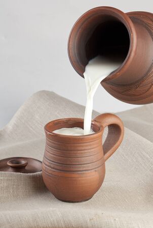 Steam of milk flowing in a mug on the tableclothの写真素材