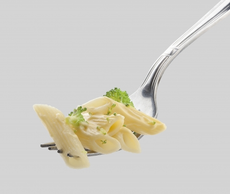 Some pasta with cheese and vegetables on the metal forkの写真素材