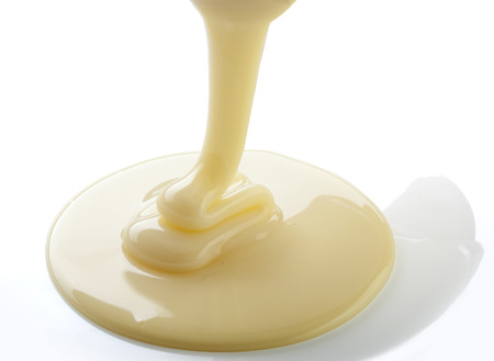 Isolated stream of yellow condensed milk on the white backgroundの写真素材