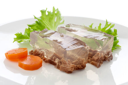 Two pieces of beef aspic with green fresh parsley and orange carrot on the white plateの写真素材