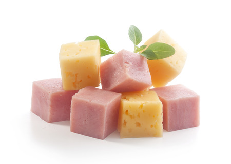 Isolated handful of ham and cheese cubes with fresh green basilの写真素材