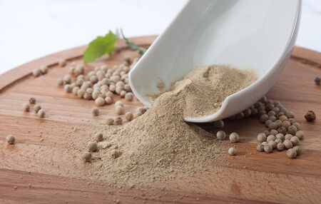Powder and whole seeds of white pepper on the wooden boardの写真素材