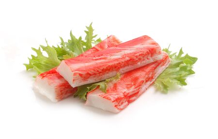 Three red crab stick with green lettuce on the white plateの写真素材