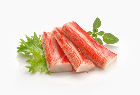 Three red crab stick with green lettuce and basil on the white plateの写真素材