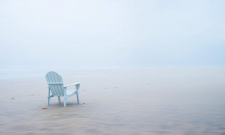 Lonely chair on white sand of tranquil beach of sea covered with mist. Generative AI.の素材