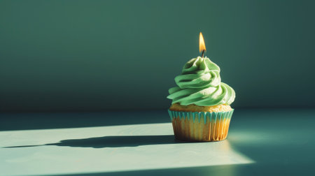 Aesthetic green cupcake with candle, dark background, copy space. Celebration anniversary concept. Generative AIの素材