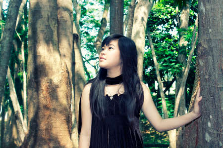 beautiful young asian girl standing beside tree at the park