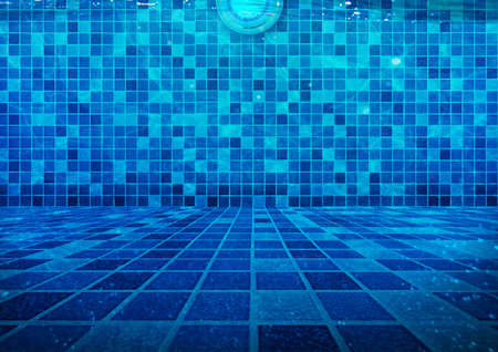 Clear Water at the Bottom of the Swimming Pool with Underwater Lighting Blue Tiles Backgroundの写真素材