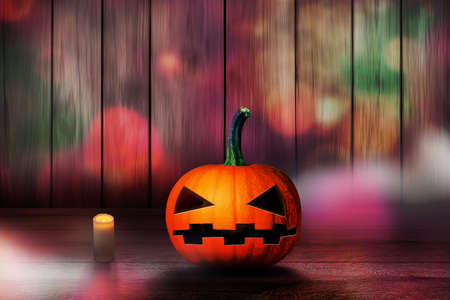 scary halloween pumpkin alone beside a candle wooden backgroundの写真素材