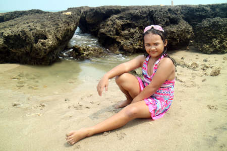 young asian girls posing in swimsuits and goggles on white sandy and rock backgroundの写真素材