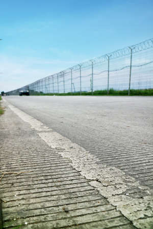 Road Outside Airport Lined by a Wire Fence