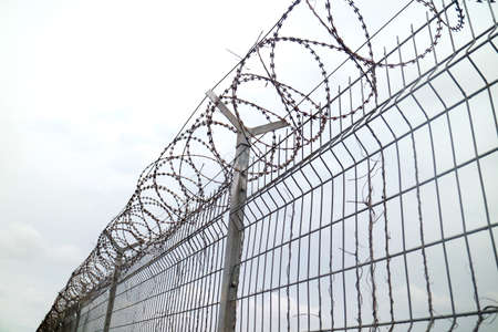 Wire Fence Airport with white skyの写真素材