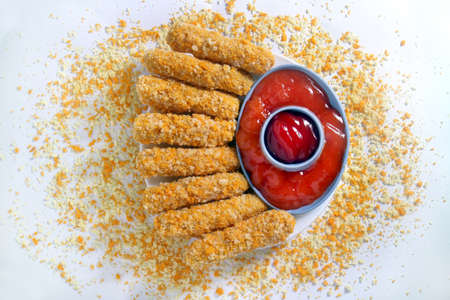 Food photography of Nugget sticks fish fried crunchy line up around with ketchup on white tray with breaded sprinkles white background top viewの写真素材