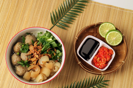 food photography of meatballs and beef skin in a bowl complete with chili sauce, soy sauce and lime wedges top viewの写真素材