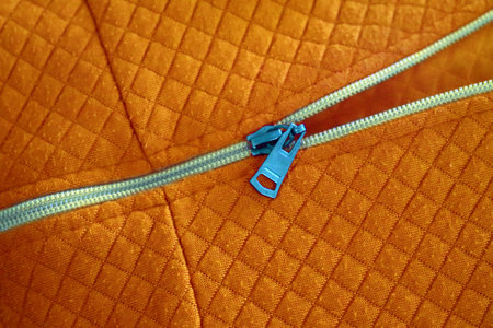 Close-Up of Zipper on Orange Quilted Fabric Surfaceの写真素材