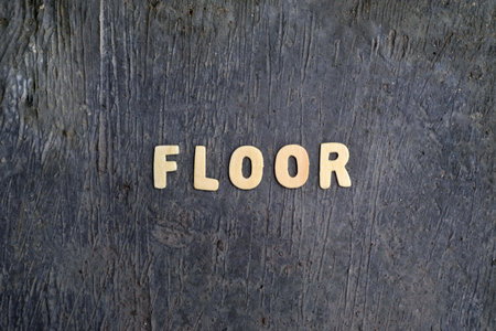 Wooden Letters Spelling Floor on Rough Concrete Surfaceの写真素材