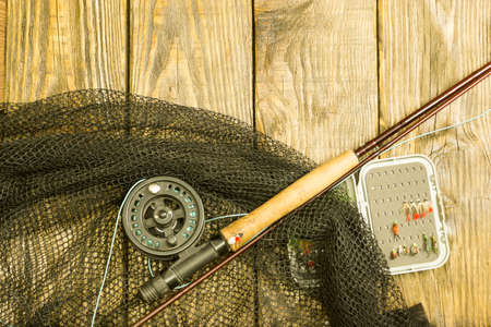 Fly fishing rod, flie and a landing on the old wooden table. All ready for fishing.の写真素材