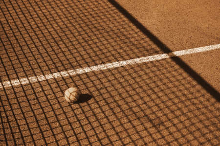 A tennis ball lies on the court in the shadowの写真素材