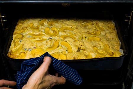 Woman hand taken out of a hot apple pies from the oven.の写真素材